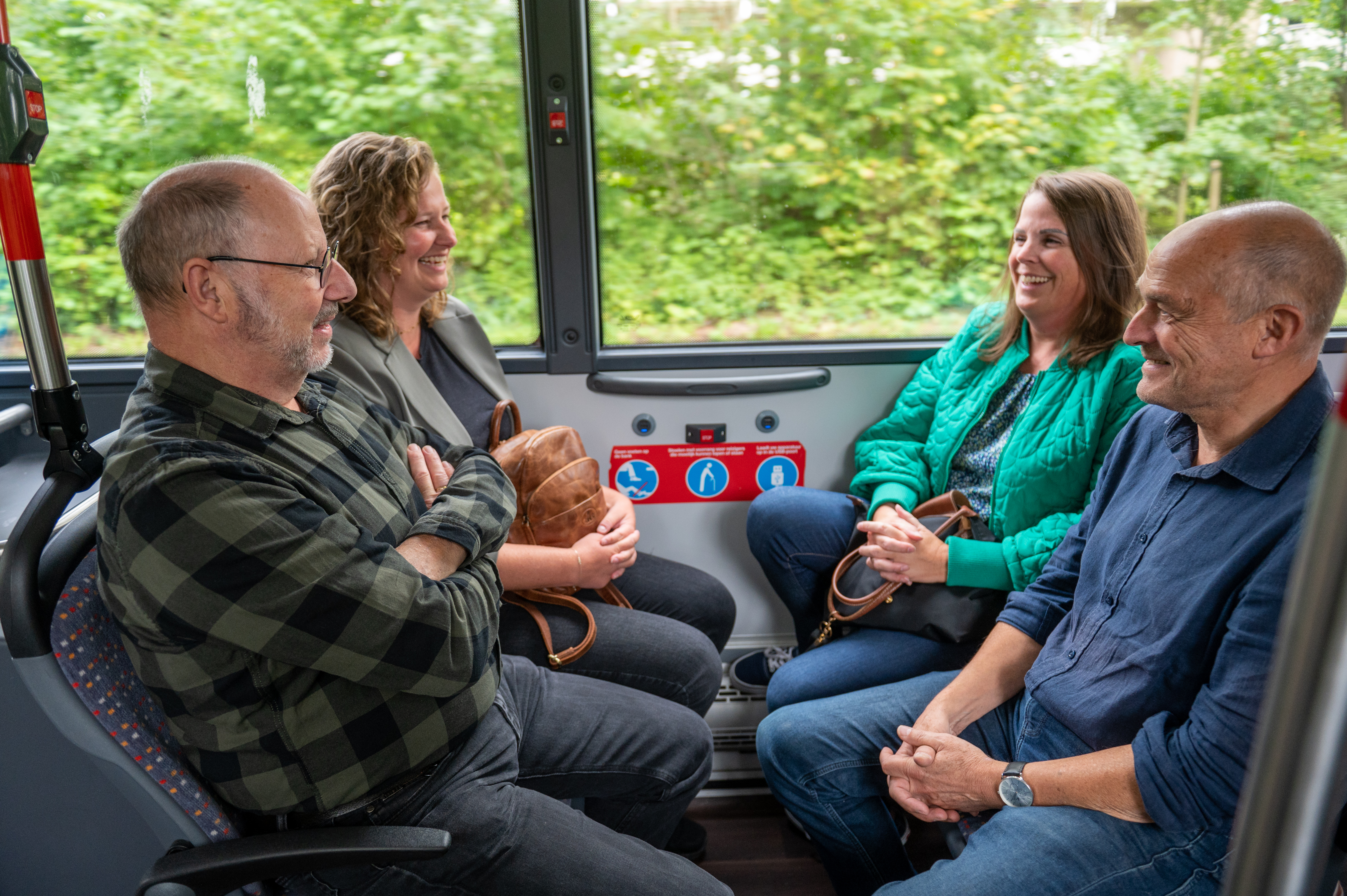 Reizigers zitten in HTM bus en lachen naar elkaar