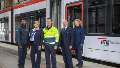 Medewerkers naast tram HTM medewerkers naast HTM tram kijken naar de camera