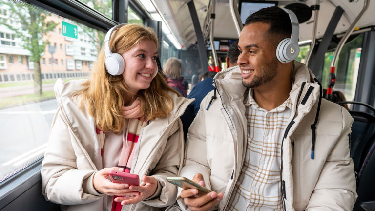 Man en vrouw luisteren samen muziek in HTM bus Man en vrouw luisteren samen muziek in HTM bus