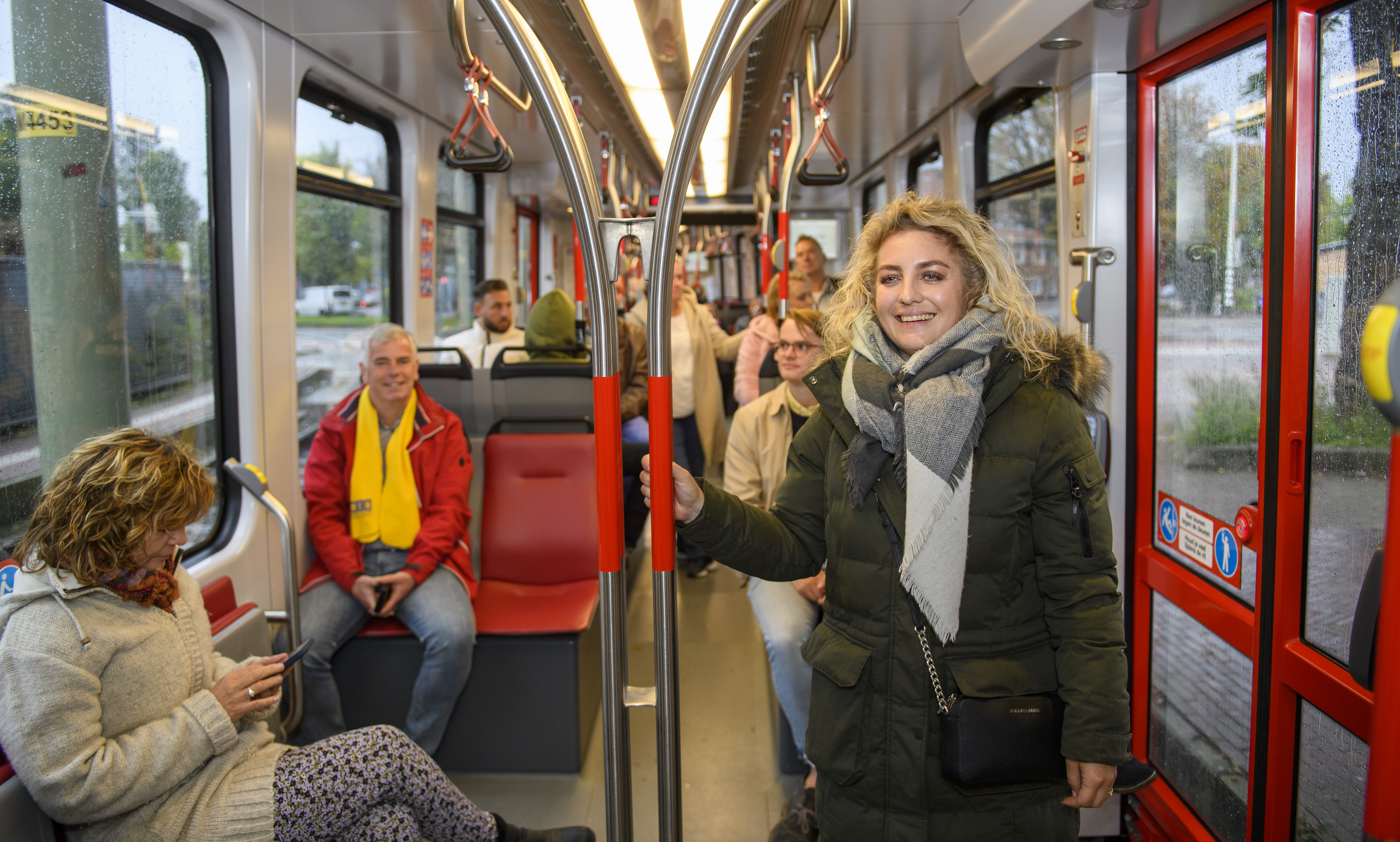 Reizigers staan en zitten in HTM tram en kijken naar de camera