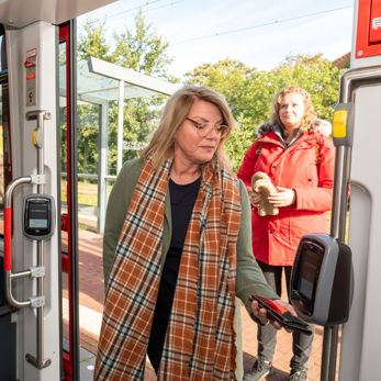 Vrouw checkt in met telefoon Reiziger checkt in met OV-pay in HTM tram
