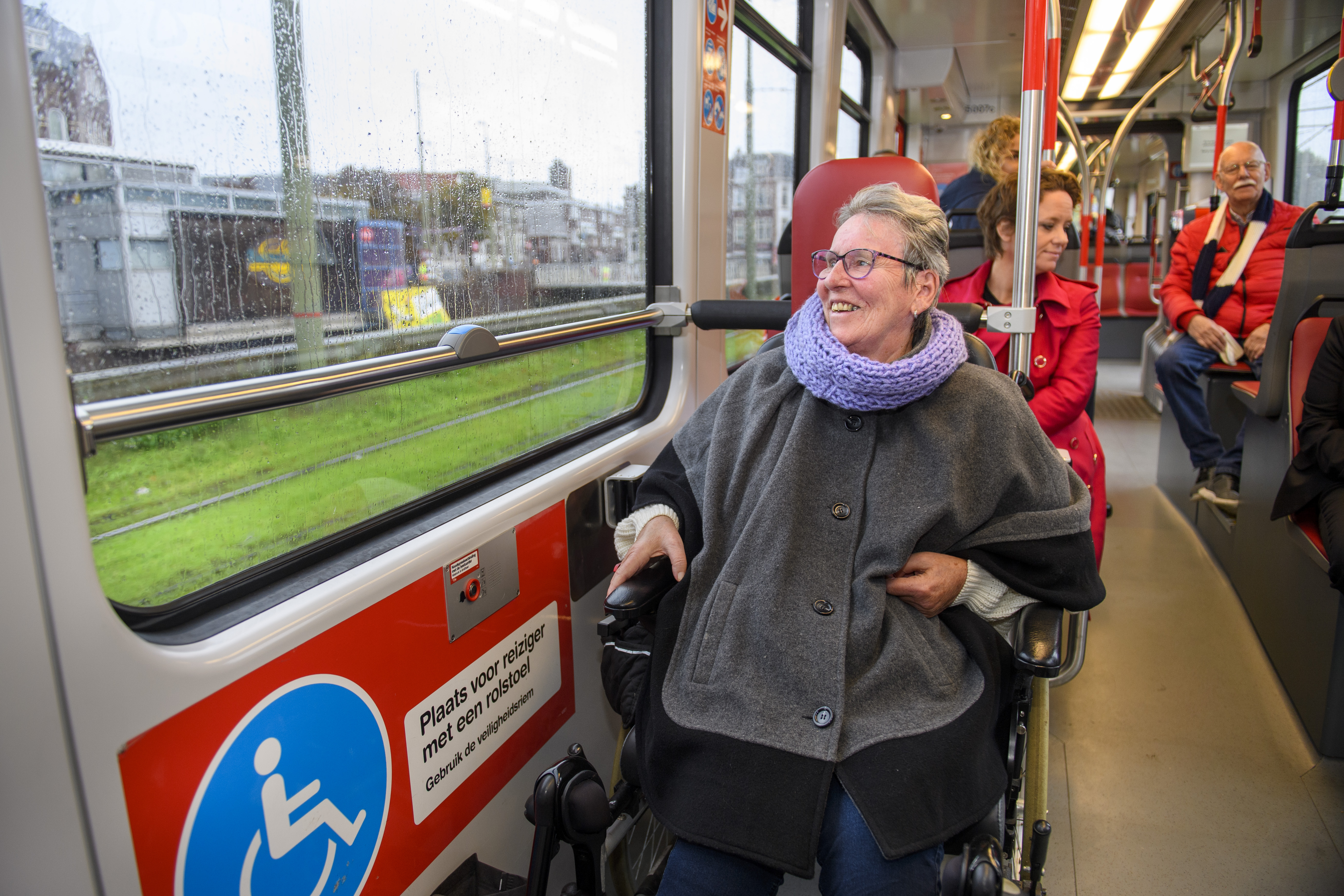 Reiziger in een rolstoel zit in HTM tram en kijkt naar buiten